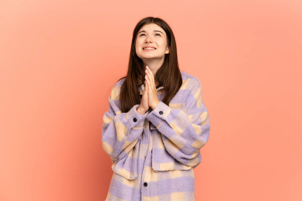 Молодая украинка, изолированная на розовом фоне, держит ладонь вместе. Человек просит что-то