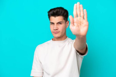 Genç, yakışıklı, beyaz bir adam, mavi bir bakkalda izole edilmiş bir şekilde duruyor.