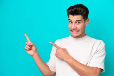 Genç, yakışıklı, beyaz bir adam, mavi bir bakkalda izole edilmiş, korkmuş ve kenarı işaret ediyor.