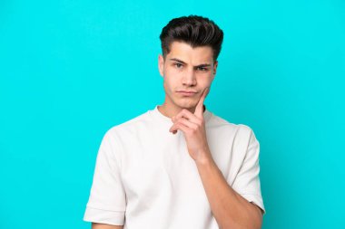 Genç, yakışıklı, beyaz bir adam mavi fırında izole edilmiş ve düşünüyor.