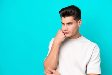 Genç, yakışıklı, beyaz bir adam, yorgun ve sıkılmış bir ifadeyle mavi fırında tek başına.