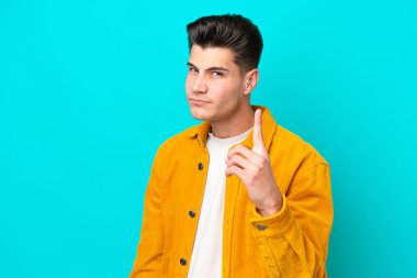 Genç, yakışıklı, beyaz bir adam mavi fırında izole edilmiş hayal kırıklığına uğramış ve ön tarafı işaret ediyor.