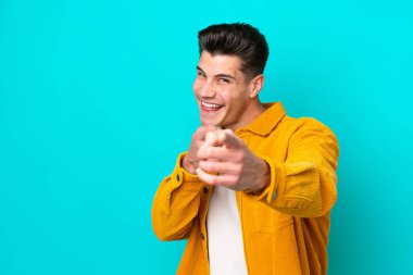 Genç, yakışıklı, beyaz bir adam, mavi bir fırında tek başına, önü işaret ediyor ve gülümsüyor.