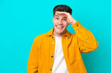 Genç, yakışıklı, beyaz bir adam, mavi bir bakkal sahasında izole edilmiş, uzaklara bakıyor.