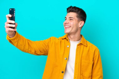 Genç yakışıklı beyaz adam mavi fırında izole edilmiş bir şekilde selfie çekiyor.