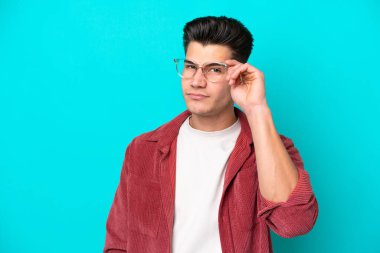 Genç yakışıklı beyaz adam mavi fırında tek başına, gözlüklü ve sinirli bir ifadeyle.