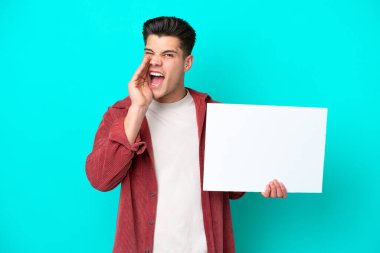 Genç, beyaz bir adam mavi bir bakkalda izole edilmiş, elinde boş bir levha ve bağırıyor.