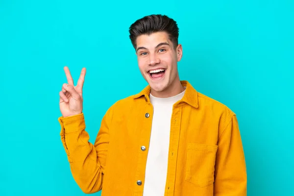 Jonge Knappe Blanke Man Geïsoleerd Blauwe Bakcground Glimlachend Met Overwinningsteken — Stockfoto