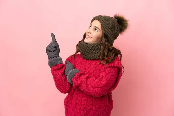 Liten Flicka Med Vinter Hatt Isolerad Rosa Bakgrund Pekar Upp — Stockfoto