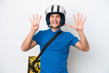 Beyaz arka planda termal sırt çantalı beyaz tenli genç bir adam dokuz parmaklı sayıyor.