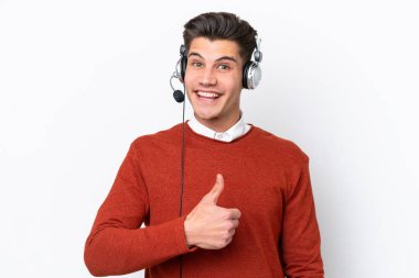Beyaz arka planda izole edilmiş bir kulaklıkla çalışan beyaz pazarlamacı beyaz bir adam baş parmak işareti yapıyor.