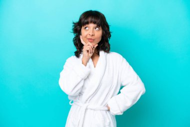 Bornozlu, mavi arka planda izole edilmiş genç bir kadın.