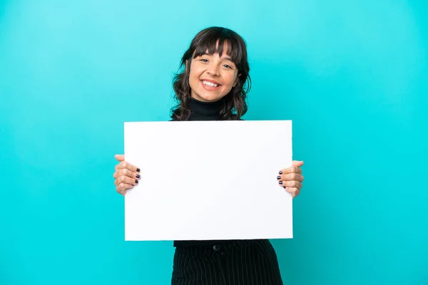 一个年轻的拉丁女人 被蓝色的背景隔离着 手里拿着一张空空的标语牌 脸上带着快乐的表情 — 图库照片