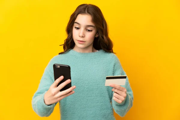 Маленька Біла Дівчинка Ізольована Жовтому Тлі Купуючи Мобільним Телефоном Кредитною — стокове фото