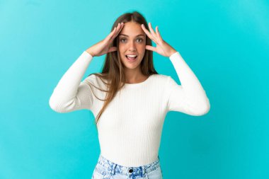 Sürpriz ifade ile izole mavi arka plan üzerinde genç kadın