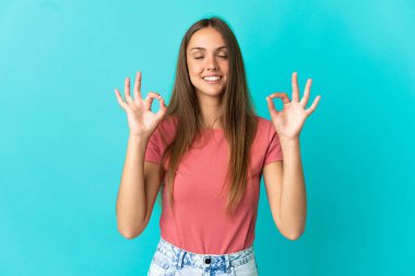 Zen pozunda soyutlanmış mavi arka planı olan genç bir kadın.