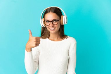 Soyutlanmış mavi arka planda müzik dinleyen genç bir kadın.