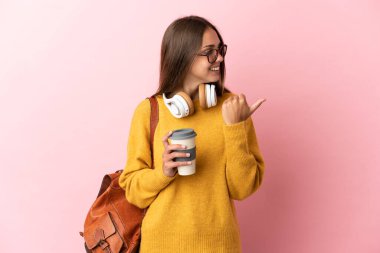 Tecrit edilmiş pembe arka planı olan genç bayan bir ürünü sunmak için kenarı işaret ediyor.