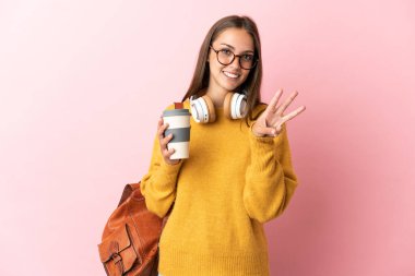 Soyutlanmış pembe arka planı olan genç kız mutlu ve parmaklarıyla üçe kadar sayıyor.