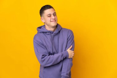 Sarı arka planda izole edilmiş genç beyaz adam gülüyor.