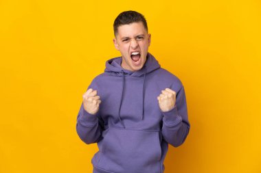 Sarı arka planda izole edilmiş genç beyaz adam kötü bir durum yüzünden hayal kırıklığına uğradı.