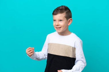 Küçük çocuk mavi arka planda izole bir şekilde zaferi kutluyor.