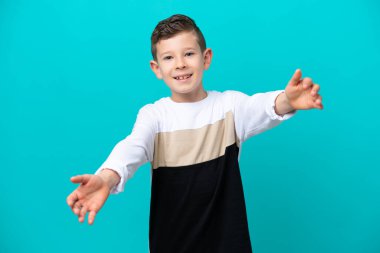 Küçük çocuk mavi arka planda izole edilmiş sunuyor ve davet ediyor.