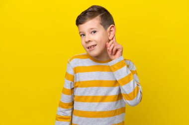 Sarı arka planda izole edilmiş küçük beyaz çocuk gülüyor.