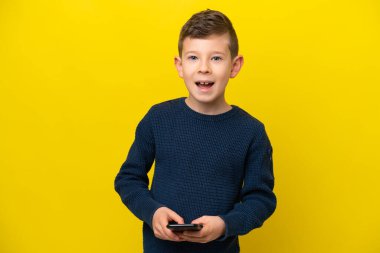 Sarı arka planda izole edilmiş küçük beyaz çocuk şaşırdı ve bir mesaj gönderiyor.