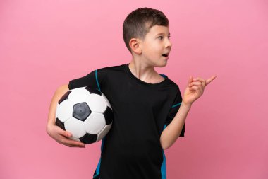 Kafkas futbolcu çocuk pembe arka planda izole edilmiş. Çözümü bulmak için parmağını kaldırıyor.
