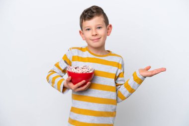 Beyaz arka planda yalıtılmış mısır gevreği kasesi tutan beyaz bir çocuk el kaldırırken şüpheye düşüyor.