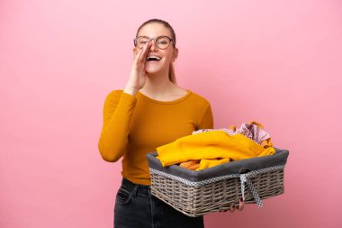 Pembe arka planda izole edilmiş çamaşır sepetini tutan beyaz bir kadın ağzı açık bağırıyor.