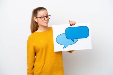 Beyaz arka planda izole edilmiş genç beyaz bir kadın konuşma balonu ikonlu bir levha tutuyor.