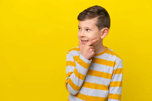 Pequeño Chico Caucásico Aislado Sobre Fondo Amarillo Mirando Hacia Lado —  Fotos de Stock