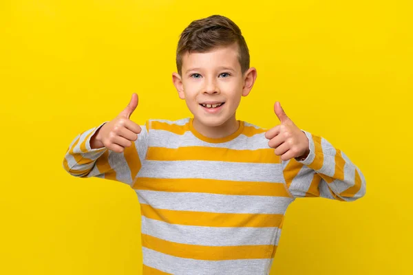 一个被黄色背景隔离的高加索小男孩举起大拇指做了个手势 — 图库照片