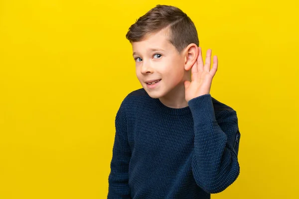 Pequeño Chico Caucásico Aislado Sobre Fondo Amarillo Escuchando Algo Poniendo —  Fotos de Stock