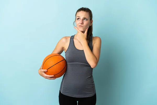 Giovane Donna Che Gioca Basket Isolato Sfondo Blu Avendo Dubbi — Foto Stock
