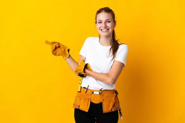 年轻的电工妇女被黄色背景隔离 手指指向侧边 — 图库照片