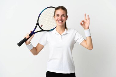 Beyaz arka planda izole edilmiş genç beyaz kadın tenis oynuyor ve tamam işareti yapıyor.