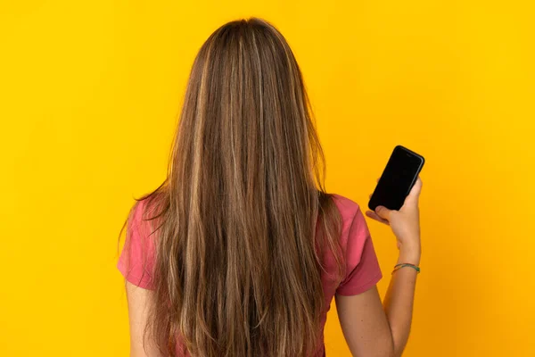 Młoda Kobieta Korzystająca Telefonu Komórkowego Żółtym Tle Tylnej Pozycji — Zdjęcie stockowe