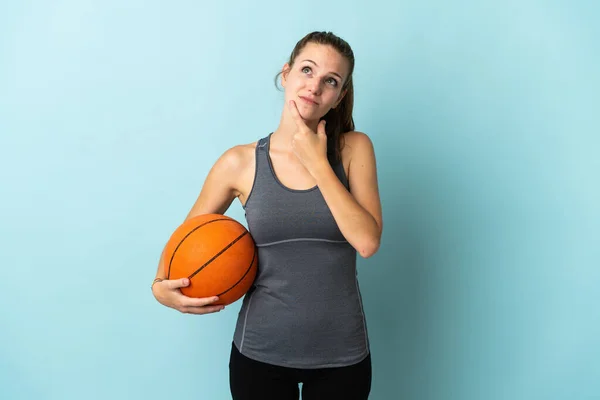 파란색 배경에서 고립된 농구를 여자가 올려다보면서 의심을 — 스톡 사진