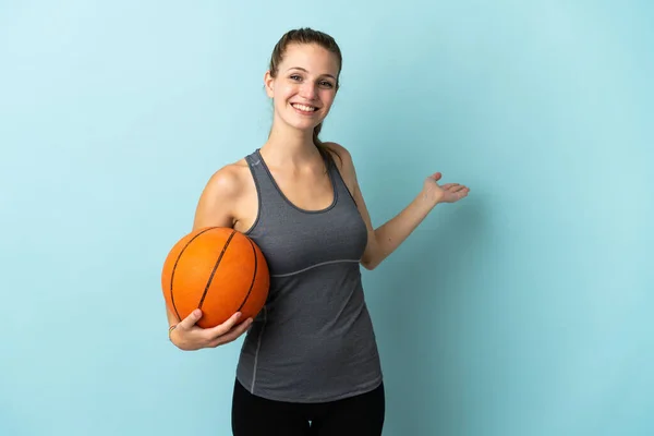 Młoda Kobieta Gra Koszykówkę Odizolowany Niebieskim Tle Wyciągając Ręce Bok — Zdjęcie stockowe
