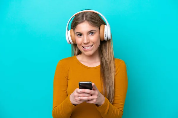 Νεαρή Καυκάσια Γυναίκα Απομονωμένη Μπλε Φόντο Ακούγοντας Μουσική Κινητό Και — Φωτογραφία Αρχείου