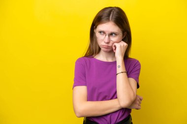 Sarı arka planda izole edilmiş genç İngiliz kadın yorgun ve sıkılmış bir ifadeyle