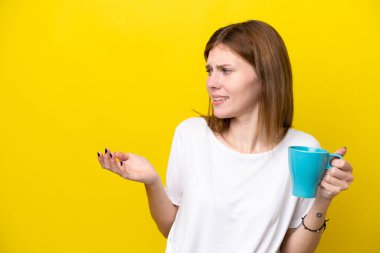 Sarı arka planda mavi kupa tutan genç ve güzel bir kadın.