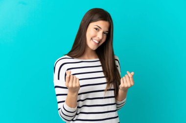 İzole edilmiş mavi arka planı olan Brezilyalı genç bir kız para hareketi yapıyor.