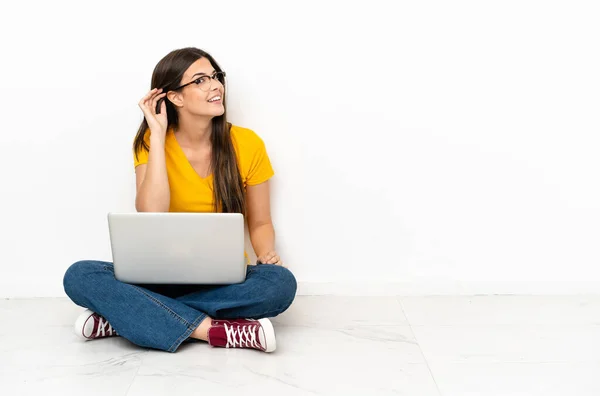 Mladá Žena Laptopem Sedí Podlaze Něco Poslouchá Tím Položí Ruku — Stock fotografie