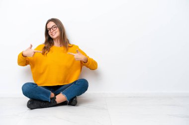 Beyaz arka planda kendini beğenmiş ve gururlu beyaz bir kadın yerde oturuyor.