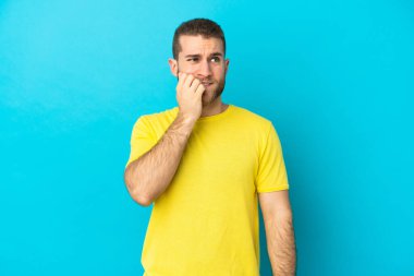 Mavi arka planda izole edilmiş yakışıklı beyaz adam biraz gergin.