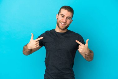 Mavi arka planda soyutlanmış yakışıklı beyaz adam gururlu ve kendini beğenmiş.